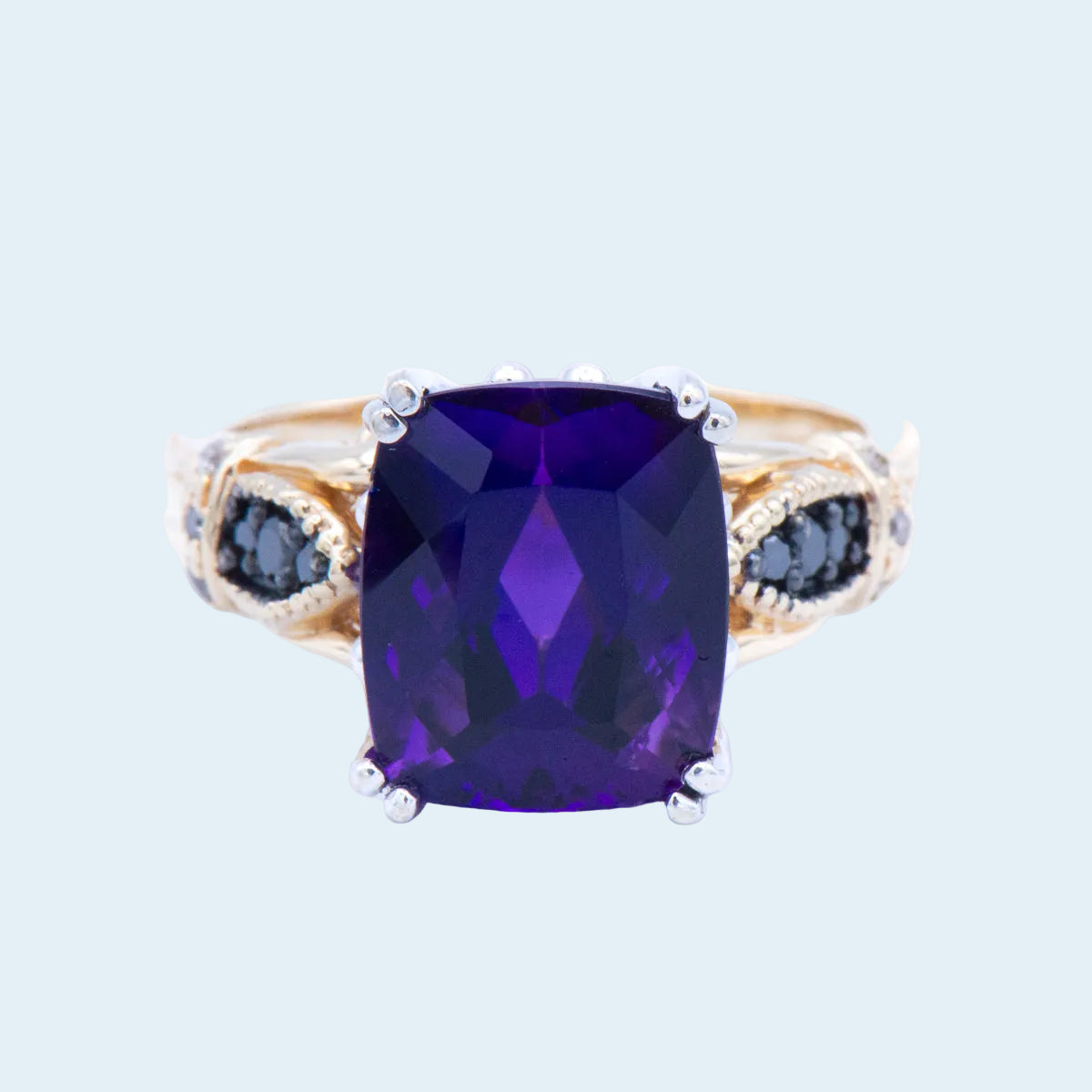 Ring with a purple gemstone and smaller black stones on a light blue background