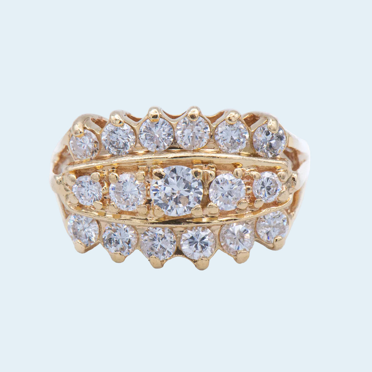 Gold ring with three rows of diamond studs on a light blue background