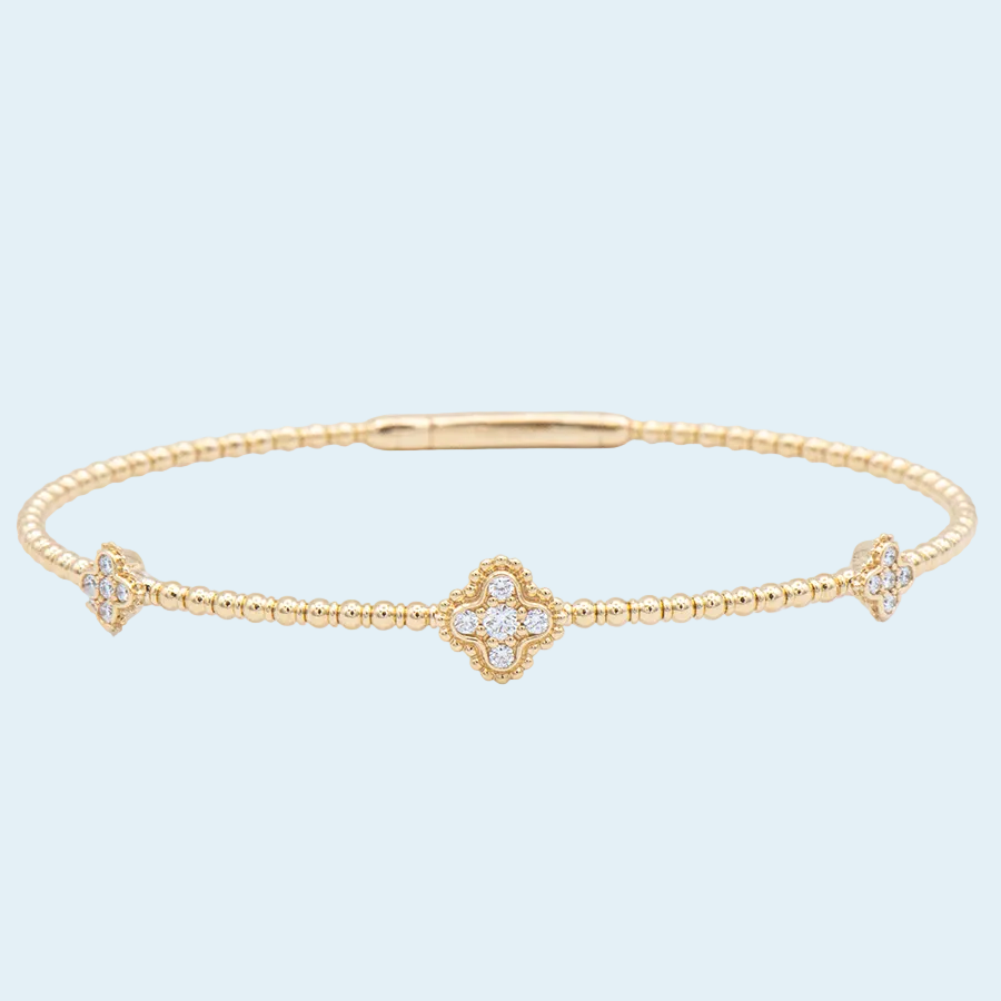 Gold bracelet with diamond accents on a light blue background