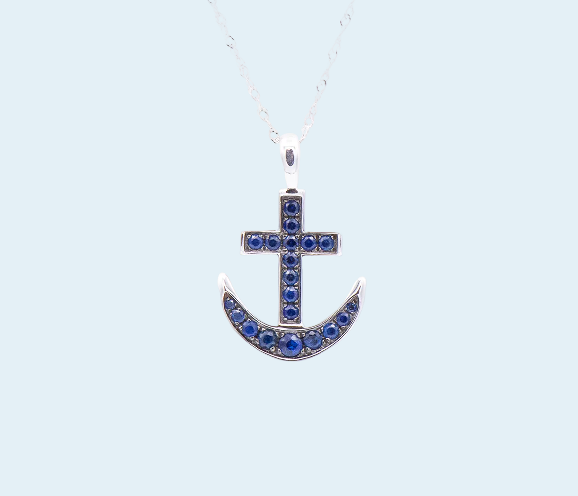 Silver anchor-shaped pendant with blue stones on a light blue background