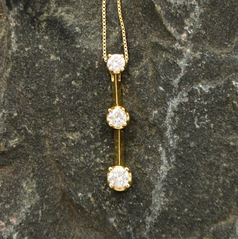 Estate 14K yellow gold diamond drop necklace by Kent Island Jewelry features three stones in a vertical pendant.