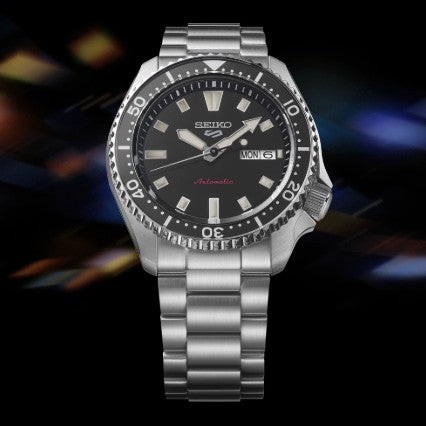 Seiko 5 Sports SS Automatic Black Dial Watch by Seiko with day-date display, stainless steel band, on a dark background.