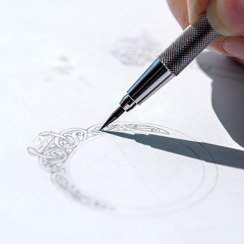Hand holding a pen and drawing a custom ring design on paper