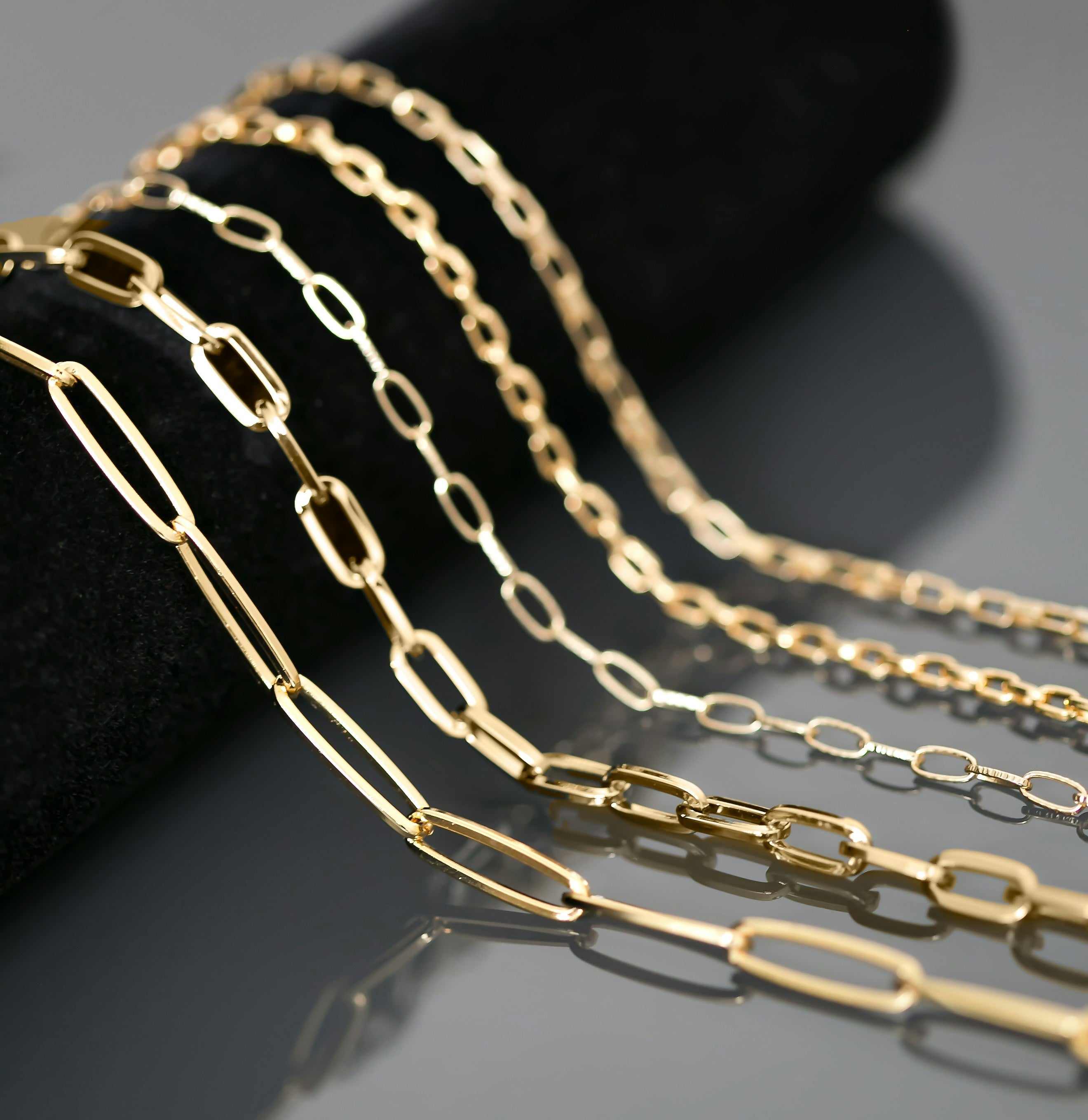 5 gold chains draped over a black display surface
