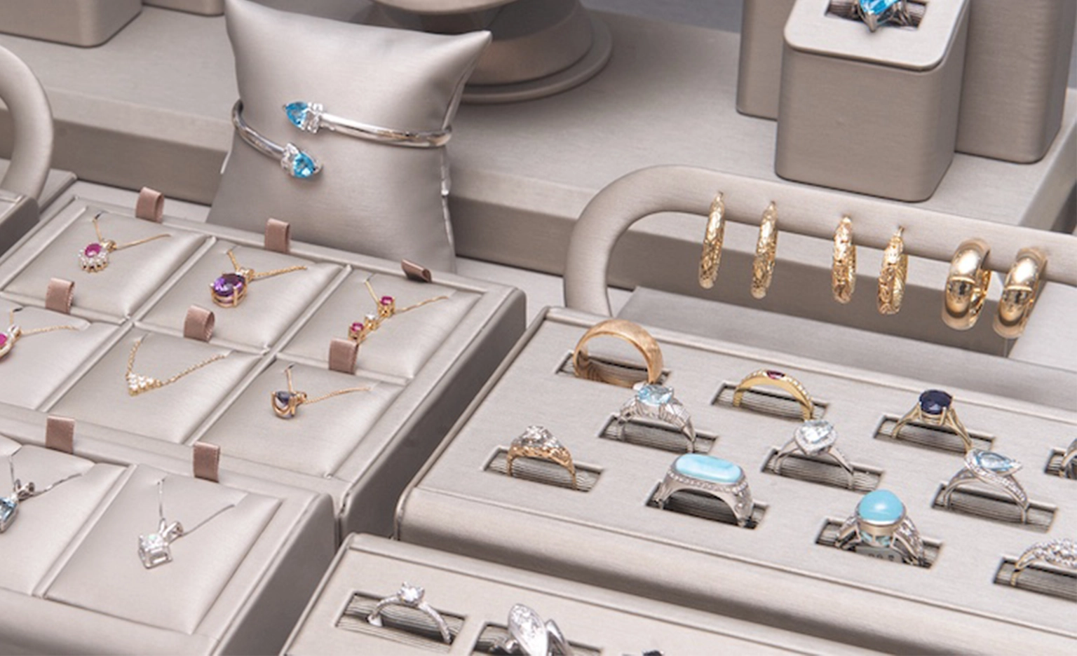 A collection of rings, necklaces, and bracelets displayed in elegant showroom cases and plinths