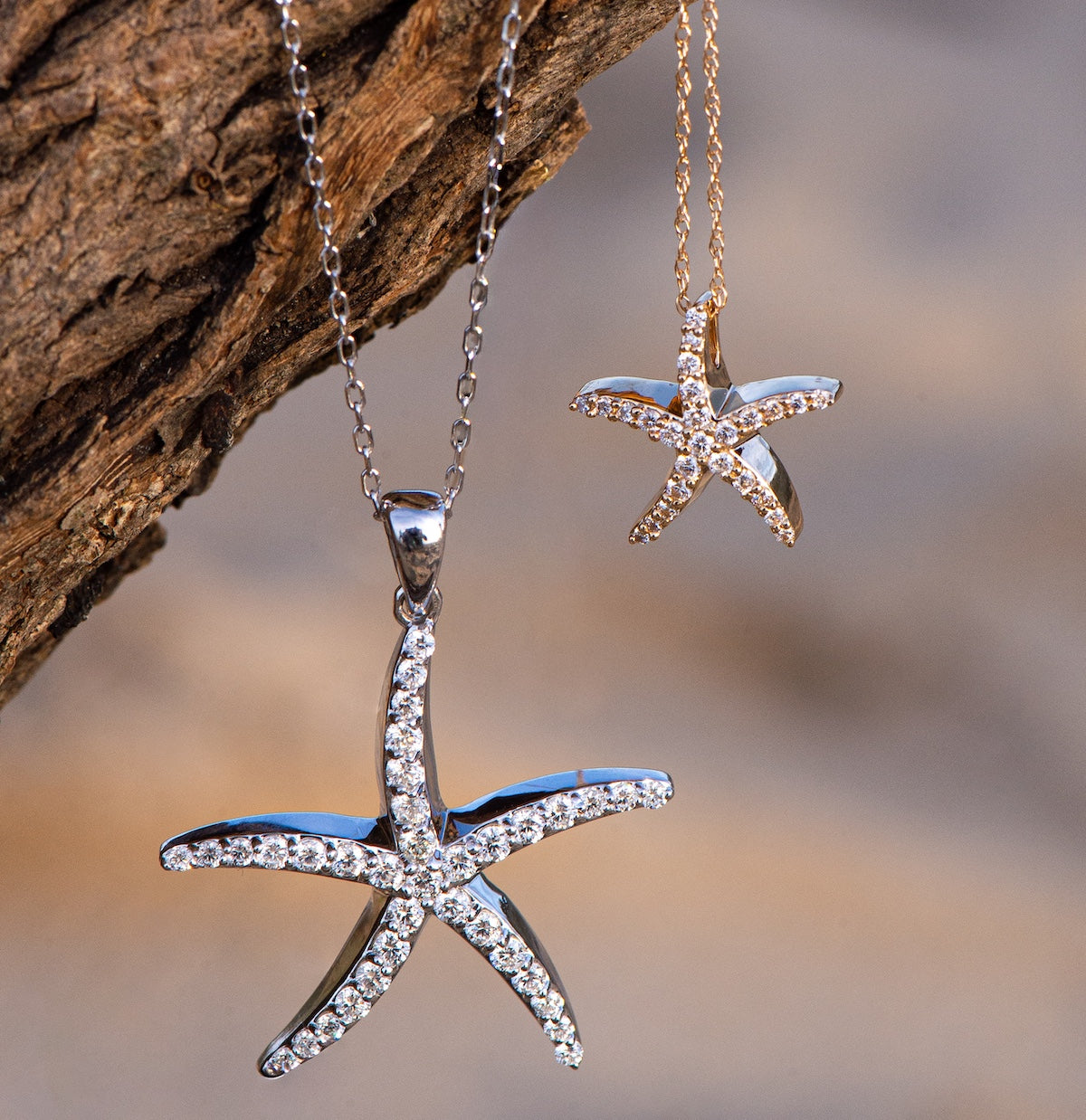 Starfish-shaped pendants with diamond accents on chains against a natural wood background