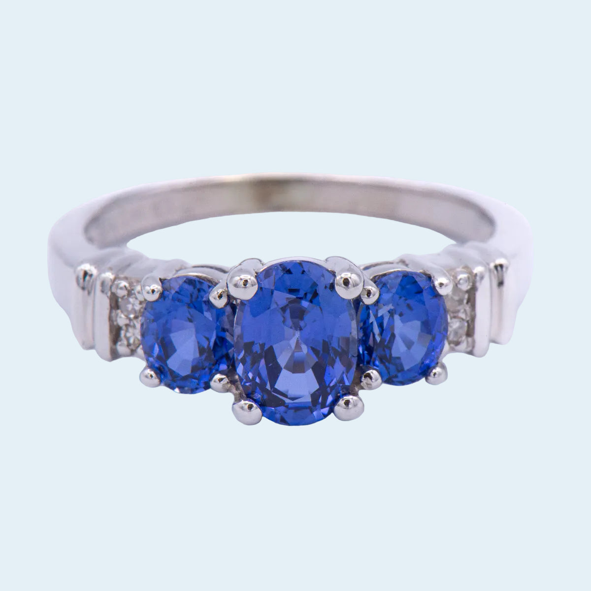 Silver ring with three blue gemstones on a white background