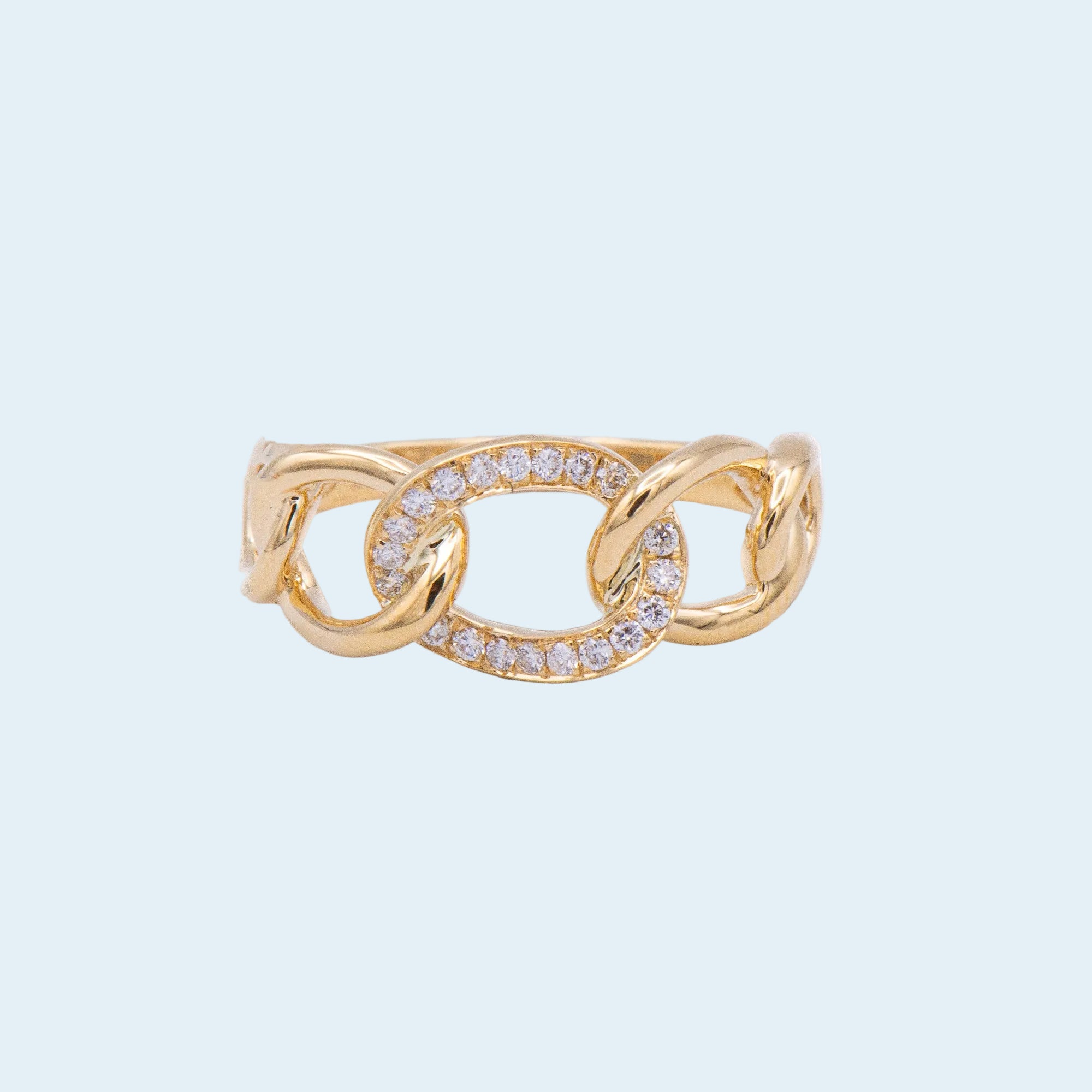 Gold ring with diamond accents on a light blue background