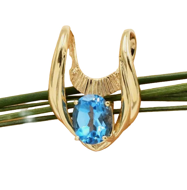 Gold pendant with a topaz gemstone seated on a rock display