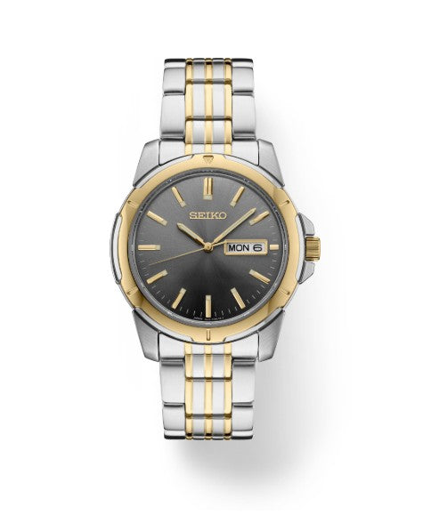 Seiko Essentials SS TT Quartz watch with gray dial, silver and gold band, and day-date display at 3 o’clock.
