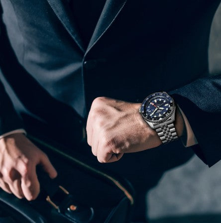 Man in a dark suit with a briefcase checks his Seiko 5 Sports SS Automatic GMT Blue Dial Watch by Seiko.