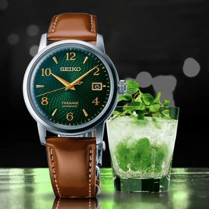 A Seiko Presage Cocktail Time SS Automatic with green dial rests by a mojito, its hue mirroring mint leaves.