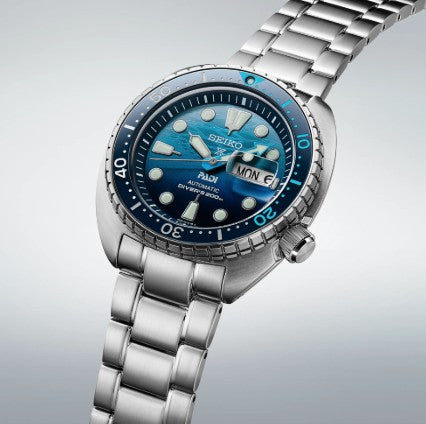 The Seiko Prosepex Diver PADI SE features a blue dial, silver bracelet, and day-date display—ideal for diving fans.