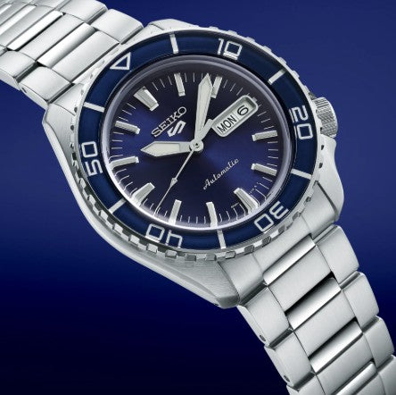 Seiko 5 Sports SS Automatic, blue dial, navy bezel, metallic band, and day-date display by Seiko.
