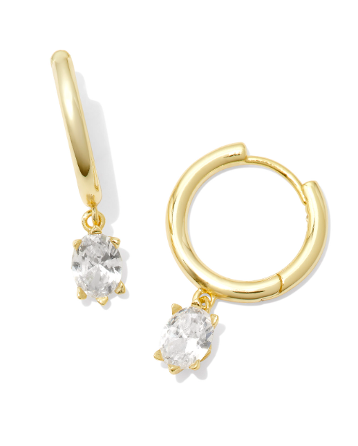 Kendra Scott CAILIN gold huggie earrings feature dangling oval white crystals, shown on a white background.
