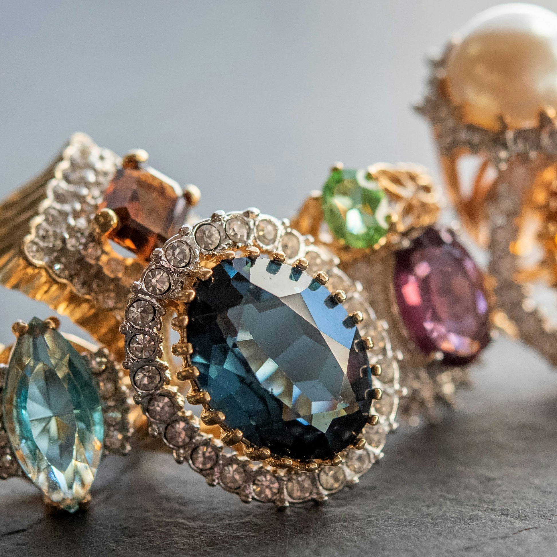 Close-up of ornate birthstone jewelry with gemstones on a textured surface