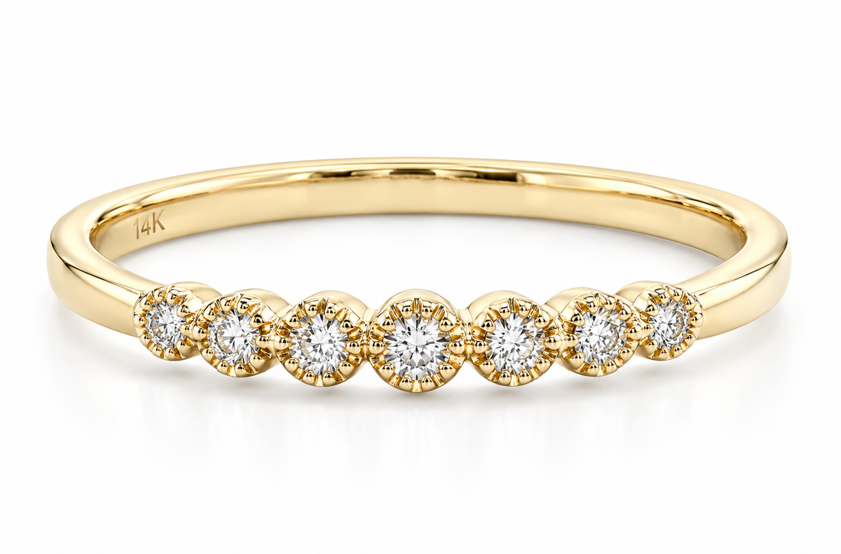 A yellow gold eternity ring featuring seven round-cut diamonds in a row of round bezel settings, shown on a clean white background.