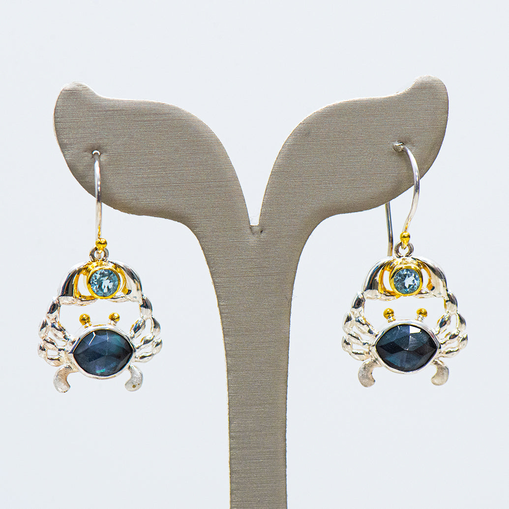 Pair of crab shaped earrings on a whale tail display stand