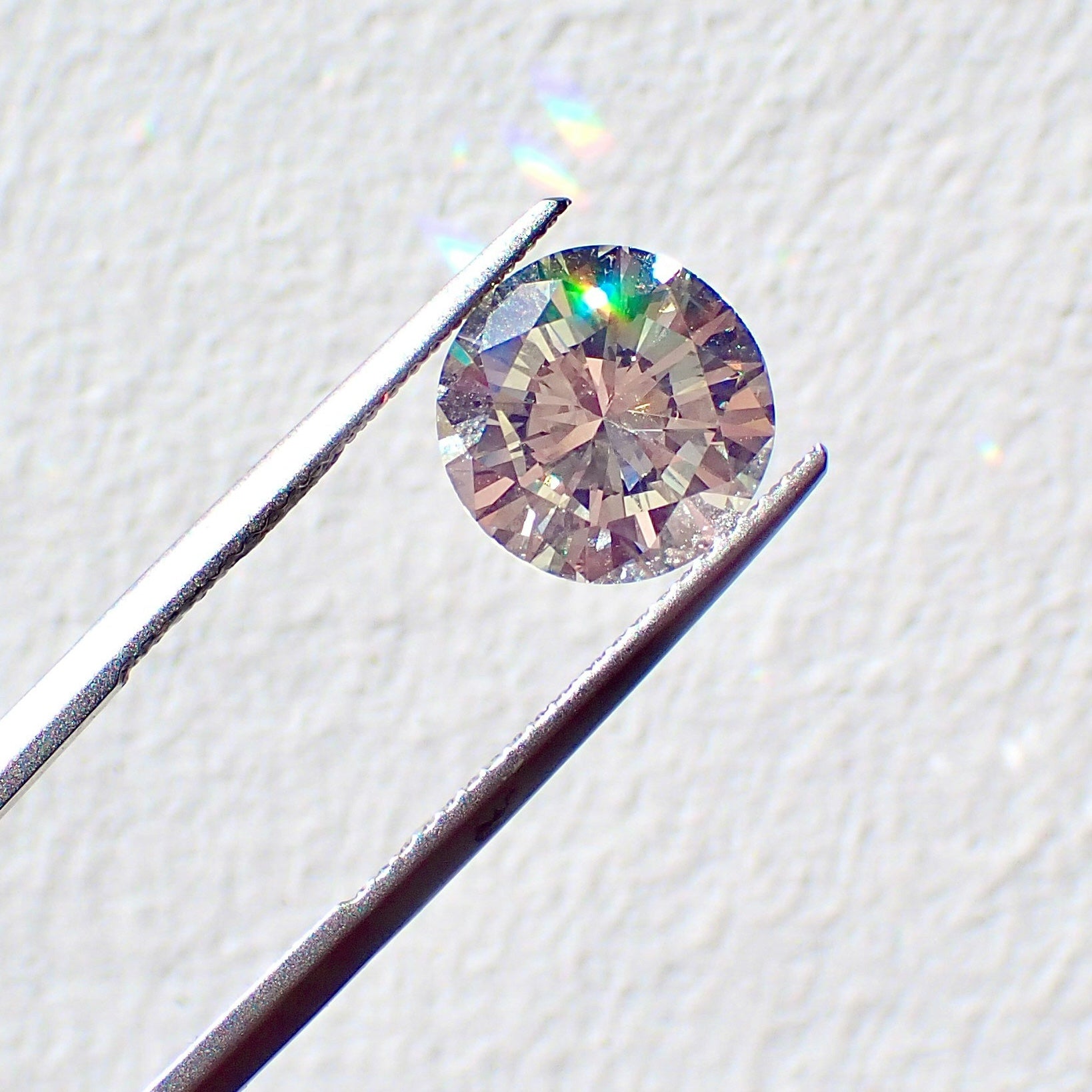 Diamond held by tweezers on a light background