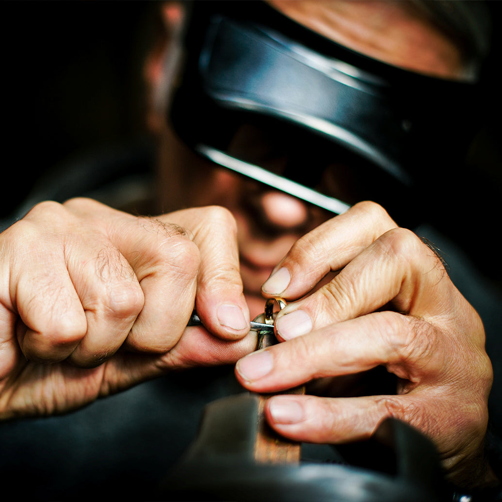 Close-up of a jeweler working on a piece of jewelry with specialized tools.