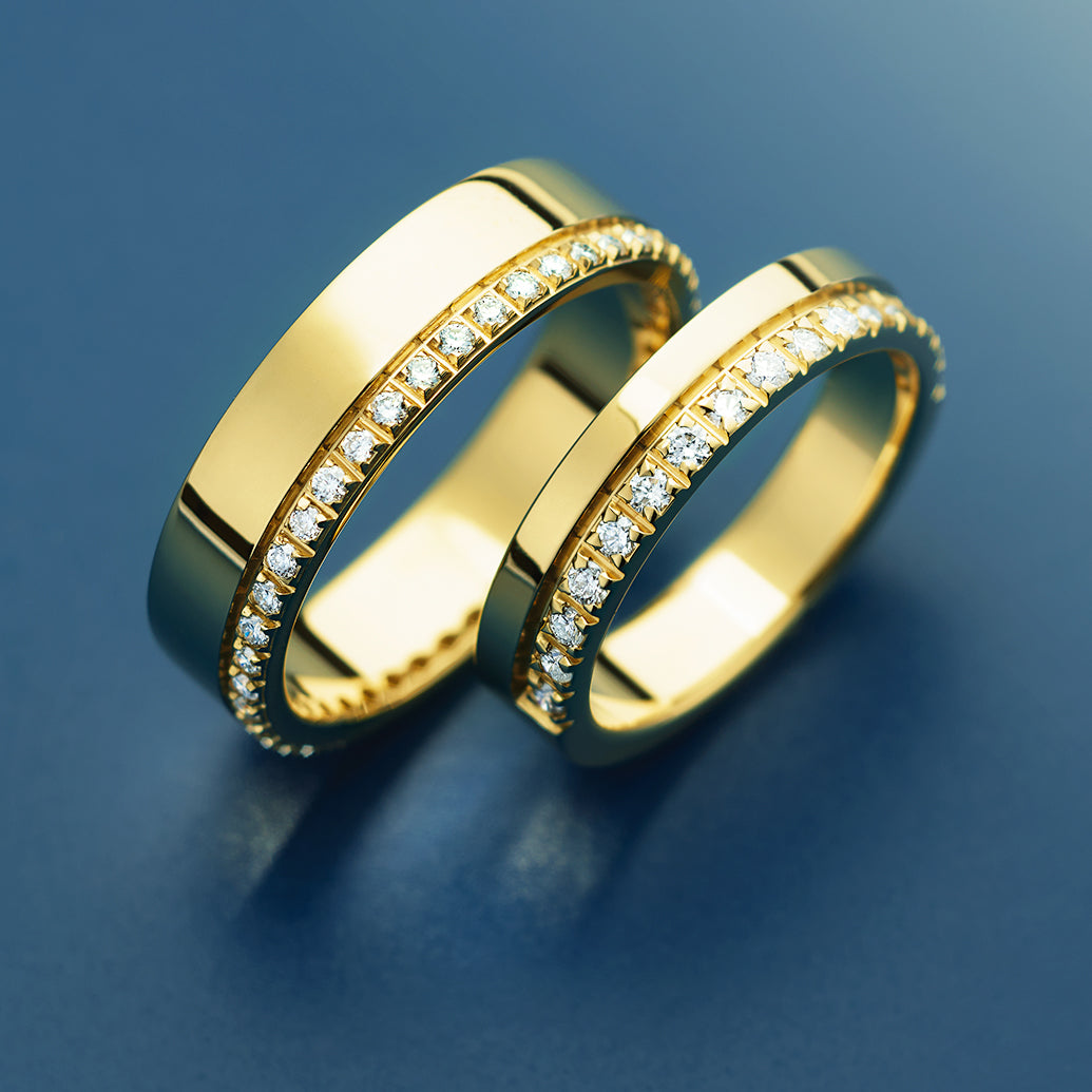 Two gold rings with diamond accents on a blue background