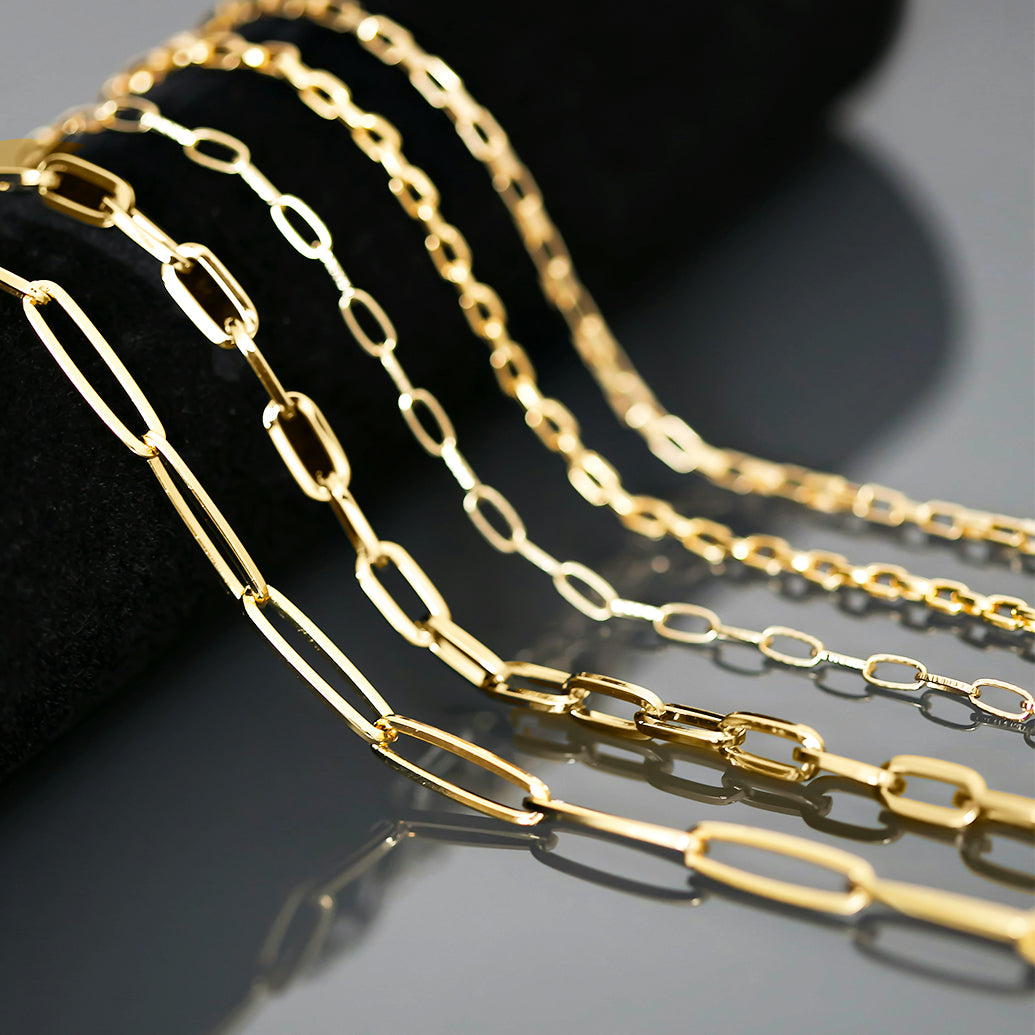 5 gold chains draped over a black display surface