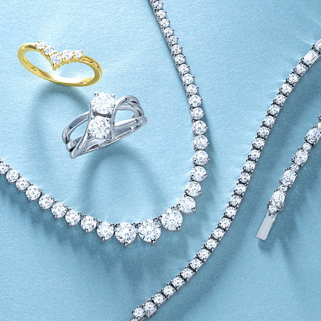 Diamond jewelry set including a ring and necklace on a light blue background