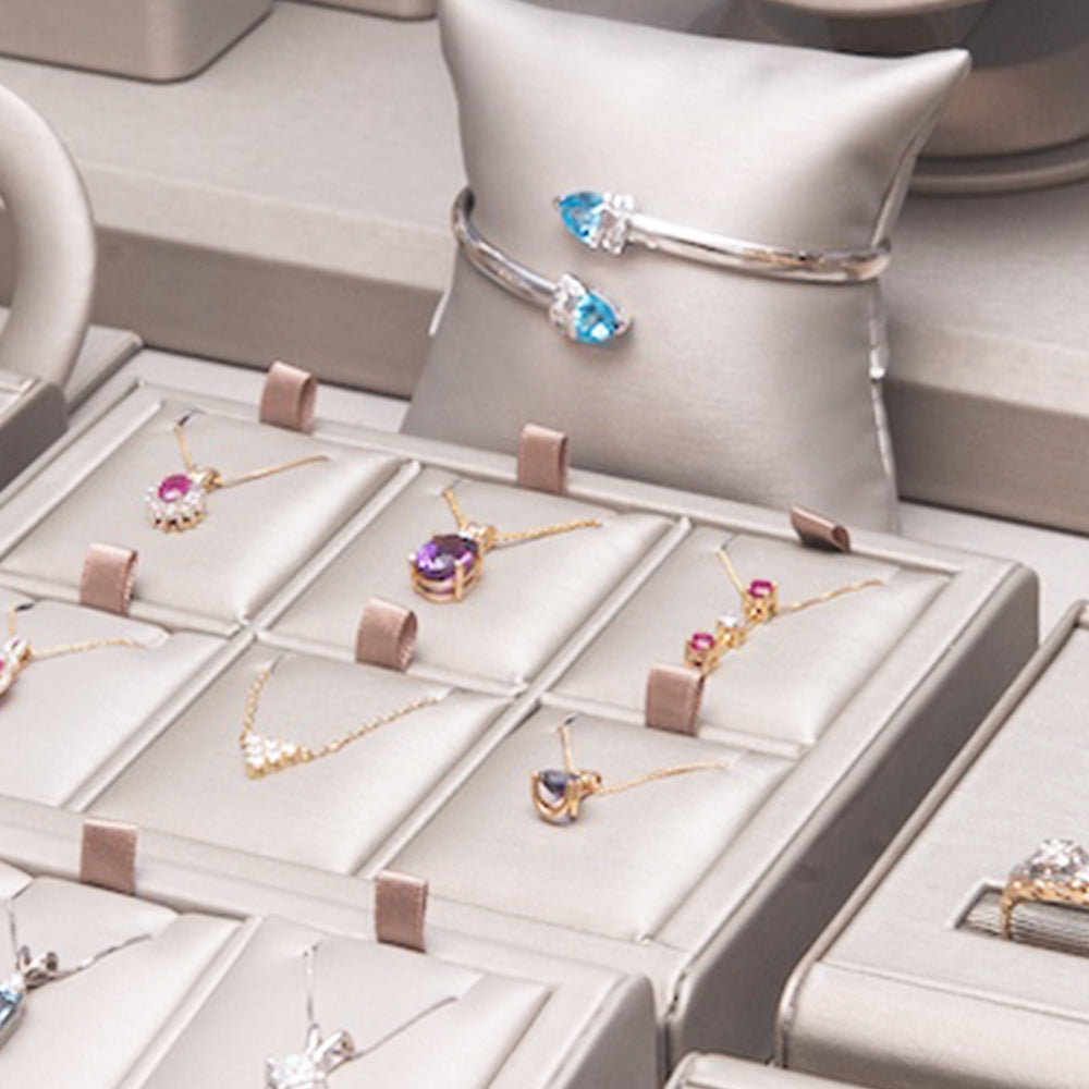 Jewelry set including necklaces and rings displayed in a box with a pillow background.
